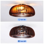 An illuminated 20 inch farmhouse caged ceiling fan with warm vintage Edison bulbs glowing through an intricate wood and metal finish mesh framework.