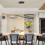 Adjustable height LED infinity pendant light hanging over a modern dining table