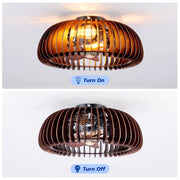 An illuminated 20 inch farmhouse caged ceiling fan with warm vintage Edison bulbs glowing through an intricate wood and metal finish mesh framework.