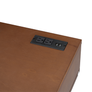 Close up view of the built-in desktop charging station with 2 AC plugs and 2 USB ports powering a phone on a walnut vanity table.