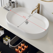 Close up of white oval ceramic top mount basin with vertical fluted groove details on a paint free moisture resistant vanity countertop.