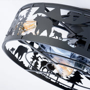 Macro close up of the matte black iron cage on a ceiling fan showing silhouette cutouts of wild bears and pine trees