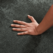 Close-up of high-density high-elastic furniture foam rebounding under hand pressure on chenille fabric.